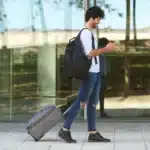 jovem carregando mala de viagem e mexendo no celular