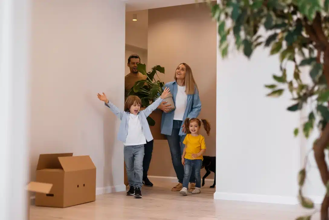 encontrar-o-imovel-ideal-familia-com-duas-criancas-entrando-na-nova-casa-com-uma-planta-nas-maos