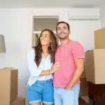 mudar-de-casa-casal-entrando-na-nova-casa-com-caixas-fechadas-e-empilhadas-atras