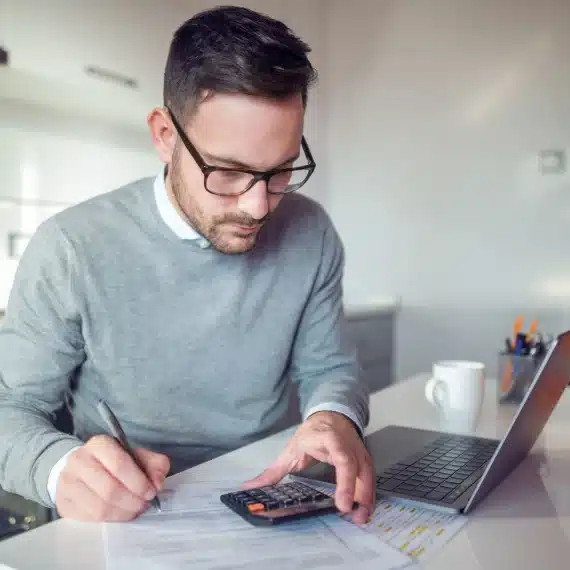 como-declarar-imposto-de-renda-de-aluguel-recebido-homem-sentado-na-cozinha-fazendo-calculos-na-calculadora