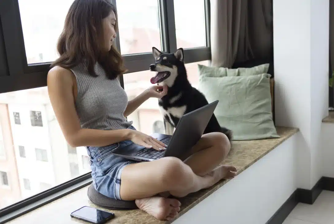 regras-para-animais-de-estimacao-em-condominio-mulher-jovem-sentada-na-janela-com-seu-cachorro-ao-lado