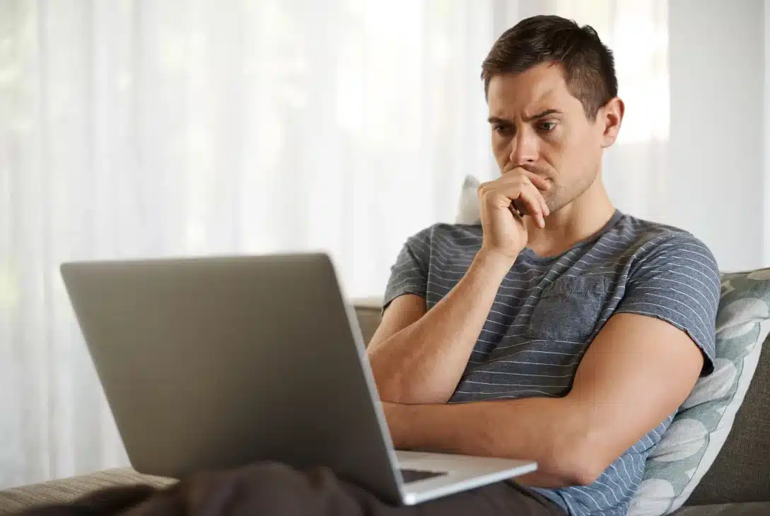 alugar-ou-comprar-imovel-homem-jovem-em-frente-ao-notebook-com-expressao-de-duvida