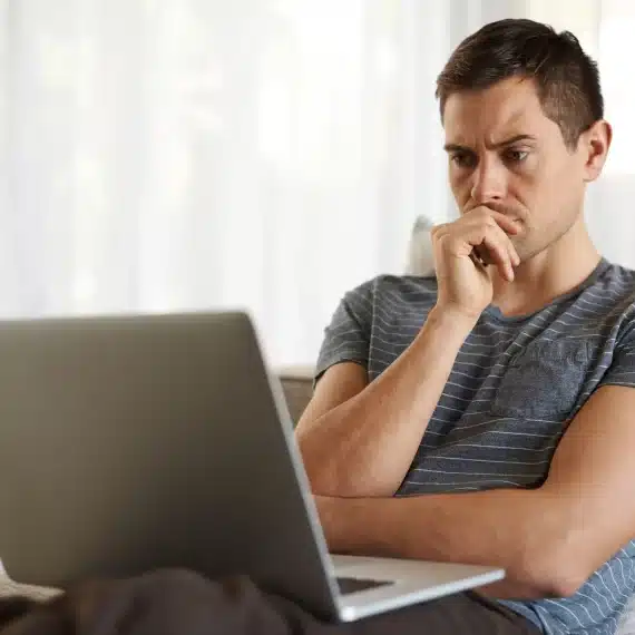 alugar-ou-comprar-imovel-homem-jovem-em-frente-ao-notebook-com-expressao-de-duvida