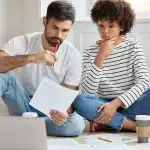 como-escolher-o-imovel-ideal-casal-sentado-no-chao-da-sala-analisando-papeis
