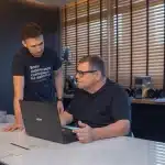 como-funciona-o-trabalho-de-um-corretor-de-imoveis-corretores-de-imovel-conversando-e-olhando-emprendimentos-no-notebook