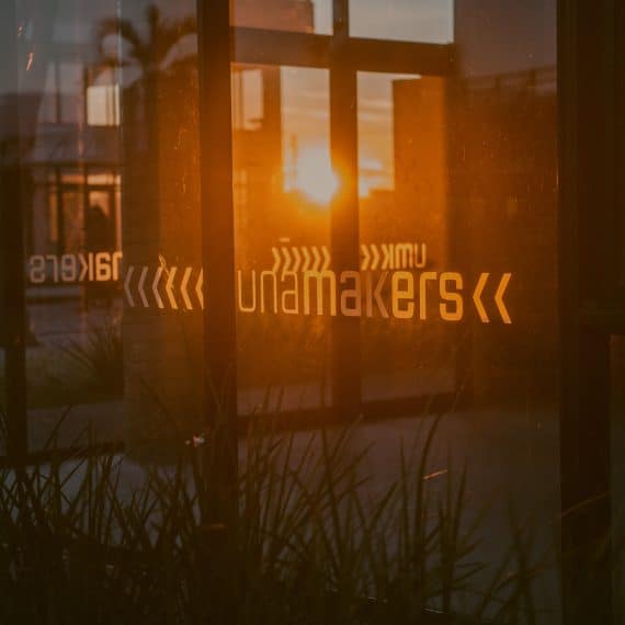 : Fachada de uma empresa de tecnologia no Parque Unamakers com a luz do sol refletindo na janela.