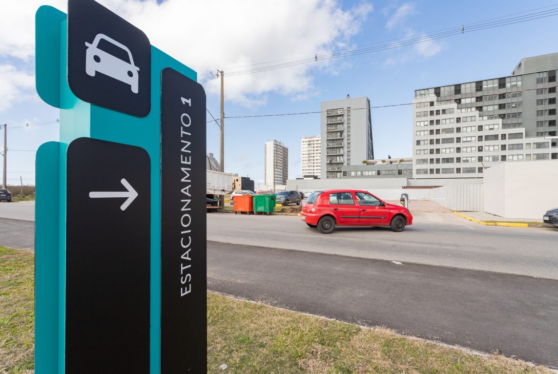 Carros estacionados em fila ao longo de uma calçada pavimentada, em área externa.
