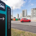 Carros estacionados em fila ao longo de uma calçada pavimentada, em área externa.